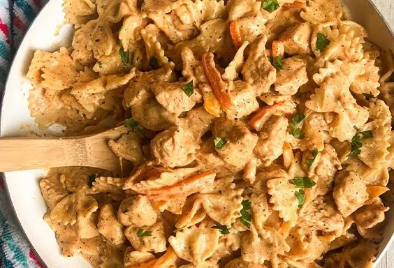 Plate of Cajun Chicken Pasta topped with parsley and surrounded by ingredients.