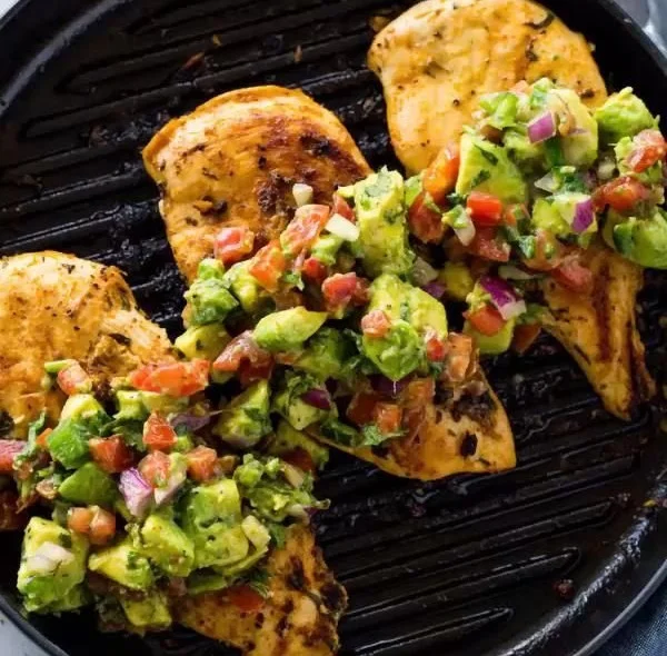 Healthy cilantro lime grilled chicken served on a plate with fresh herbs and lime.