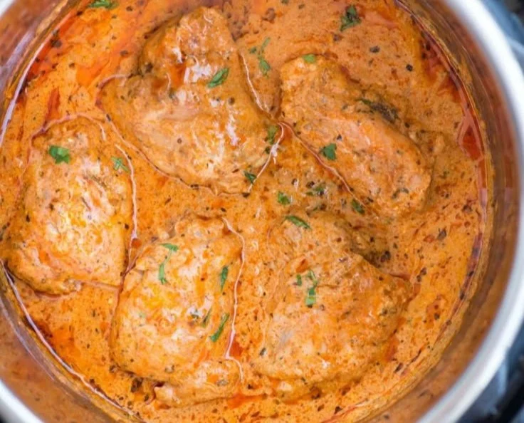 Instant Pot chicken thighs in creamy tomato sauce served with fresh herbs