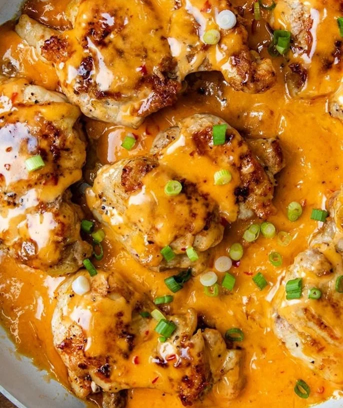 Skillet Bang Bang Chicken Thighs served on a plate with fresh herbs and sauce