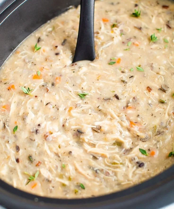 A bowl of slow cooker chicken wild rice soup garnished with herbs
