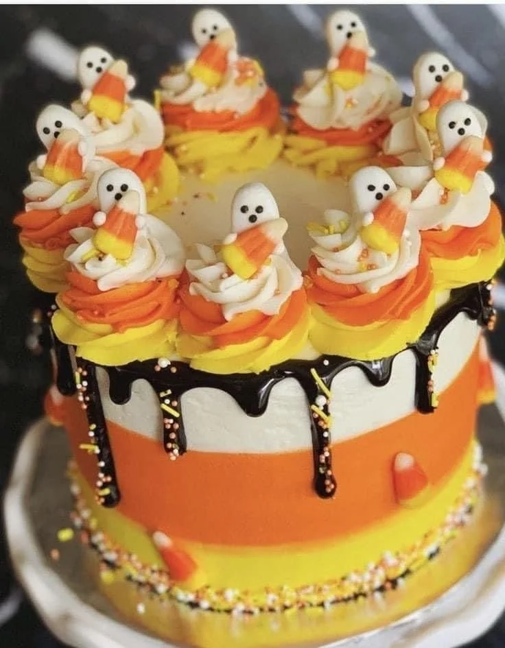 A colorful candy corn cake decorated for Halloween with layers resembling candy corn