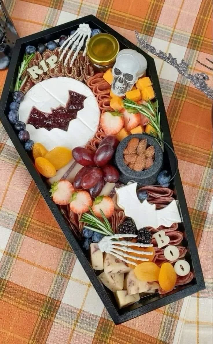 Spooky coffin charcuterie board with autumn decor and Halloween snacks
