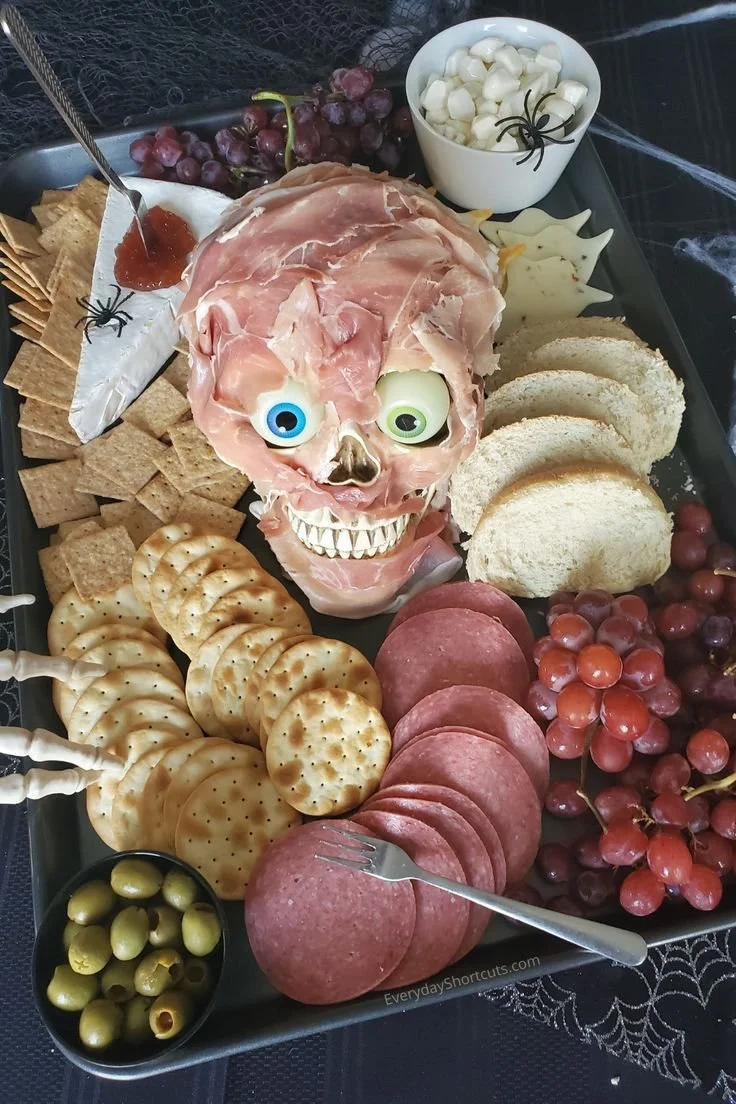 Spooky Halloween charcuterie board with themed treats, cheeses, and decor